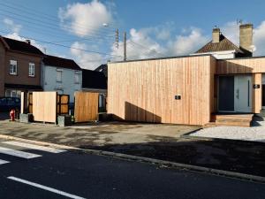 Un edificio con paneles de madera al costado de una calle. en Trinidad Vibes - Suite and Spa - Petit déjeuner inclus, en Aire-sur-la-Lys