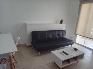 a black leather couch in a living room with a table at Departamento macrocentro Santa Fe in Santa Fe +7 photos