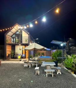 un groupe de tables de pique-nique et de parasols la nuit dans l'établissement Kurie Redbrick House, à Balik Pulau