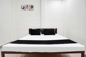 Una cama blanca con almohadas negras en una habitación en Hotel O The Moon, en Bareilly