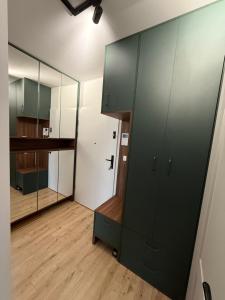 a room with green cabinets and a large mirror at REMI Apartament Biotura in Gdańsk