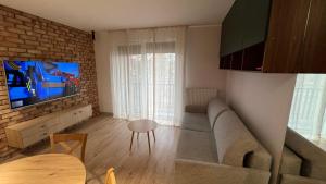 a living room with a couch and a tv at REMI Apartament Biotura in Gdańsk