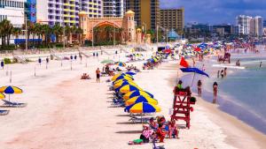 a beach with chairs and umbrellas and people on it at Wyndham Ocean Walk Penthouse Floor 1 BR Resort Condo By The Sea - Daytona Funland 1908 in Daytona Beach
