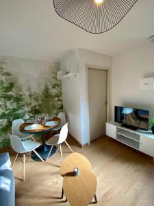 un salon avec une table, des chaises et une télévision dans l'établissement COSY Dépendance proche Saint- Émilion, à Le Fieu