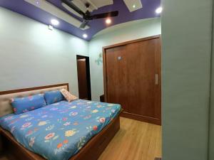 a bedroom with a bed with a blue comforter at Swami Bhakt Nivas in Tuljapur