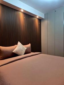 a bedroom with a large bed and a wooden wall at Apartement Seaview Studio Lv 37 at Pollux Batam by Party in Batam Center
