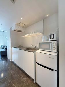 una cucina bianca con forno a microonde e bancone di b hotel Komachi 1 BR Apt Free Breakfast Included a Hiroshima