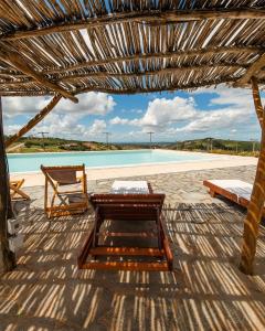 a pavilion with a table and a bench and a pool at Pousada Villas da Serra in Serra de São Bento