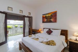 Un dormitorio con una cama con sábanas blancas y una ventana. en Taman Bali Homestay, en Sanur