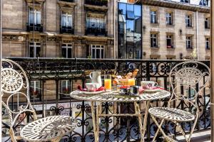 einen Tisch auf dem Balkon mit Tee und Kaffee darauf in der Unterkunft Hotel Regence Paris in Paris