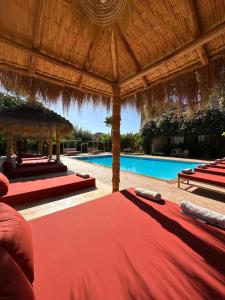 a resort with a red bed and a swimming pool at Villa Atika in El Bougaria