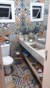 bagno con lavandino, servizi igienici e piastrelle. di Casa térrea no condomínio Atlântico Villas Club! a Osório