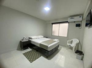 a white room with a bed and a chair in it at Amaca Hostal in Santa Cruz de la Sierra +25 photos