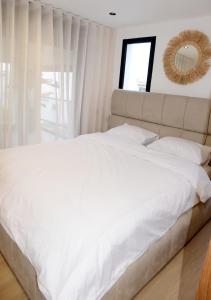 una camera da letto con un grande letto bianco e uno specchio di duplex bord de mer résidence restinga smir a Restinga Smir