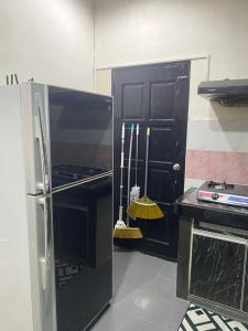 een keuken met een zwarte koelkast en een fornuis bij Pinggiran Bayu Homestay in Kuantan +8 foto's