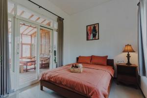 um quarto com uma cama e uma varanda com uma mesa em Rajabali Villa Batu em Tlekung