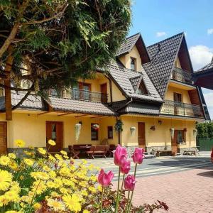 a large yellow house with flowers in front of it at Pokoje gościnne Małgorzata i Piotr Bobek in Zakopane