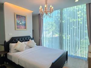 ein Schlafzimmer mit einem Bett mit einem Kronleuchter und einem großen Fenster in der Unterkunft Relax home surrounded by nature near town 15 min in Chiang Mai