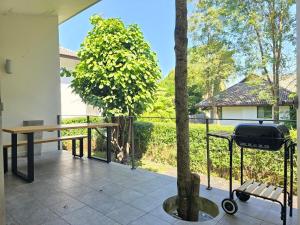ein Grill auf einer Terrasse mit einem Baum in der Unterkunft Relax home surrounded by nature near town 15 min in Chiang Mai