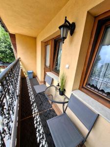 a balcony with two chairs and a table and windows at Pokoje gościnne Małgorzata i Piotr Bobek in Zakopane