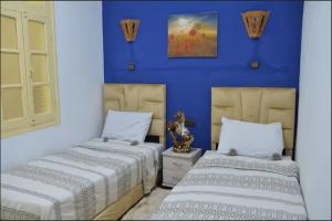 two beds in a room with blue walls at Riad Bladi Essaouira in Essaouira