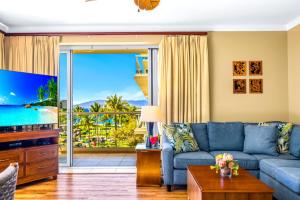 un salon avec un canapé bleu et une télévision dans l'établissement KBM Resorts FREE CAR Honua Kai Konea Oceanfront 2-Bedroom Condo with Private BBQ Large Balcony HKK-201, à Kaanapali Airport