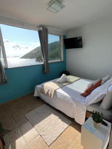 ein Schlafzimmer mit einem Bett und einem großen Fenster in der Unterkunft Estalagem pé na areia in Arraial do Cabo + 150 Fotos
