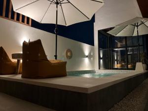 una piscina con una sombrilla, una silla y una mesa en Puspa Nirwana Villa, en Kerobokan