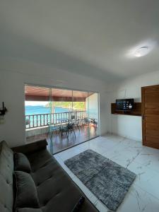 ein Wohnzimmer mit Couch und Balkon in der Unterkunft Estalagem pé na areia in Arraial do Cabo