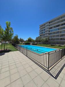 a swimming pool with a fence next to a building at Rancagua Lujo y comodidad Depto con Piscina y Estacionamiento in Rancagua