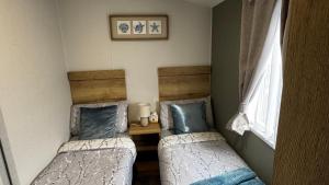 two twin beds in a room with a window at Big Boss Caravan-Camber Sands,Sleep 8, Free Wi-Fi, Netflix, Parking in Camber