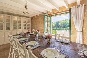 Un comedor con una mesa y un gran ventanal. en La Mouy - Périgord Noir - Farmhouse with pool, en Mauzens-et-Miremont
