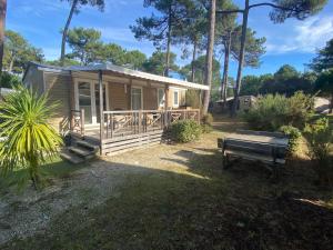 ein kleines Haus mit einer Veranda und einer Bank in der Unterkunft Tohapi camping Atlantic Club in Montalivet-les-Bains
