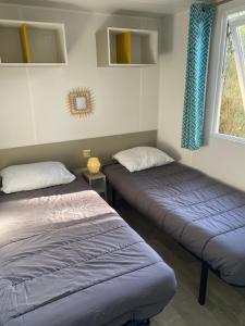 zwei Betten in einem Zimmer mit blauen Vorhängen in der Unterkunft Tohapi camping Atlantic Club in Montalivet-les-Bains