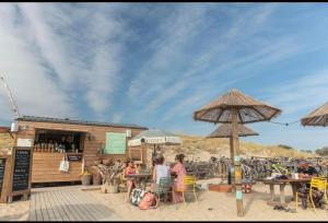 eine Gruppe von Menschen sitzt an einem Tisch mit einem Regenschirm in der Unterkunft Tohapi camping Atlantic Club in Montalivet-les-Bains + 8 Fotos