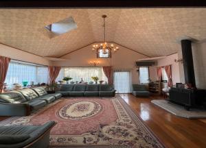 un grand salon avec un canapé et une télévision dans l'établissement ペンションあけまの森, à Daisen