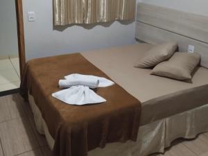 a bed with two white towels on top of it at Hotel Vitória - Guaíra in Guaíra