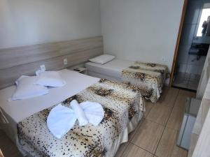 a room with two beds and a mirror at Hotel Vitória - Guaíra in Guaíra