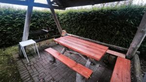 a wooden picnic table and a white chair under a shelter at Jaunrūtiņas dīķis in Salaspils