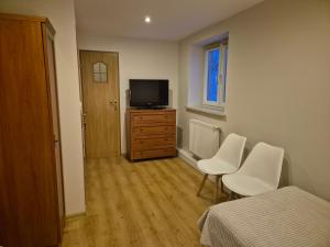 - une chambre avec 2 chaises blanches et une télévision dans l'établissement Orzechowa Zagroda, à Nowa Słupia 6 autres photos