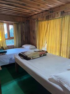 Dos camas en una habitación con cortinas amarillas. en Paldor Peak Guest House, en Thāngjet