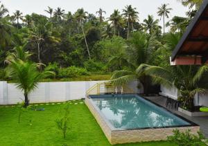a swimming pool in a yard next to a house at MeadowView Cottage Marari in Mararikulam