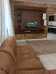 un canapé marron dans un salon avec une télévision dans l'établissement Casa ampla e aconchegante, à Foz do Iguaçu