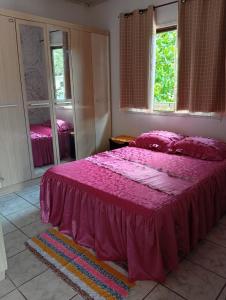 une chambre avec un lit avec un couvre-lit rose dans l'établissement Casa ampla e aconchegante, à Foz do Iguaçu