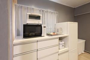 Il comprend une cuisine blanche équipée d'un four micro-ondes et d'un réfrigérateur. dans l'établissement くつろぎのお宿 やわや 駅北, à Toyama 13 autres photos