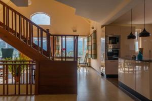 a kitchen and living room with a wooden stairway at Yellow Tulip Luxury Villa by LexStays - Coonoor in Kolakambe +20 photos