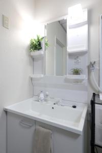 ein weißes Badezimmer mit Waschbecken und Spiegel in der Unterkunft くつろぎのお宿 やわや 駅北 in Toyama + 15 Fotos