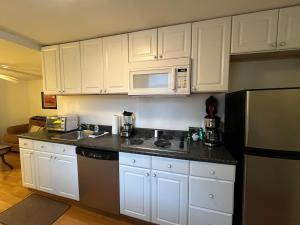 a kitchen with white cabinets and a black refrigerator at Gulf Stream House - Hammondsport Getaway Apartment Unit 11 in Hammondsport