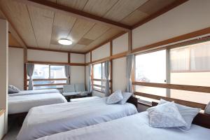 zwei Betten in einem Zimmer mit zwei Fenstern in der Unterkunft くつろぎのお宿 やわや 駅北 in Toyama