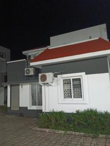 una casa blanca con techo rojo por la noche en Vg paradise, en Covelong